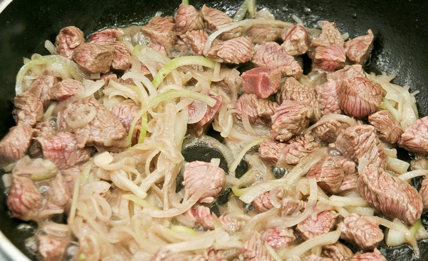 1. Этап. Говядина с черносливом и грибами: Масло разогрейте на сковороде. Жарьте в нём мясо с луком в течение двух минут на максимальном огне.