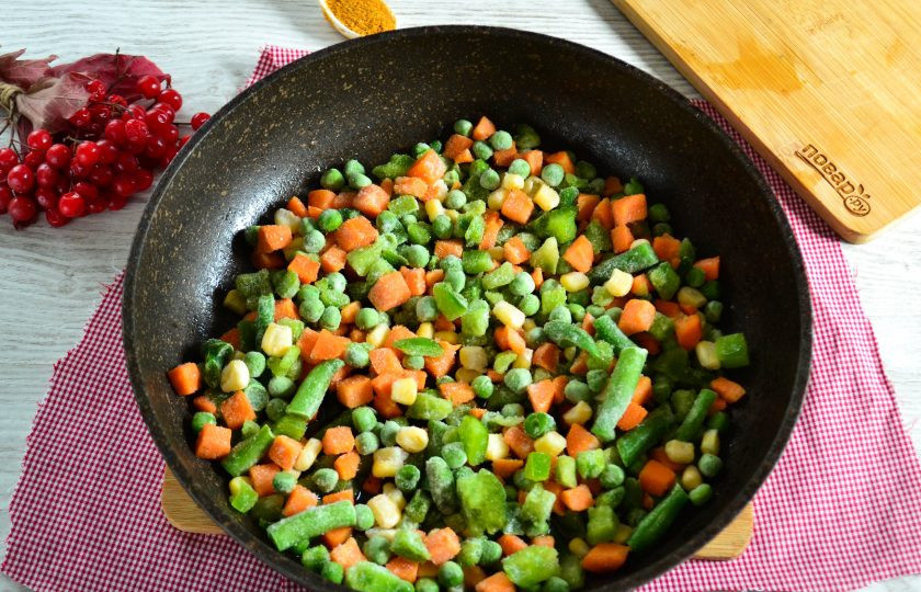 1. Этап. Рис с замороженными овощами: Разогрейте в сковороде растительное масло, положите чеснок. Когда чеснок начнет отдавать аромат, выложите в сковороду замороженные овощи. Обжарьте в течение 10 минут на среднем огне до мягкости.