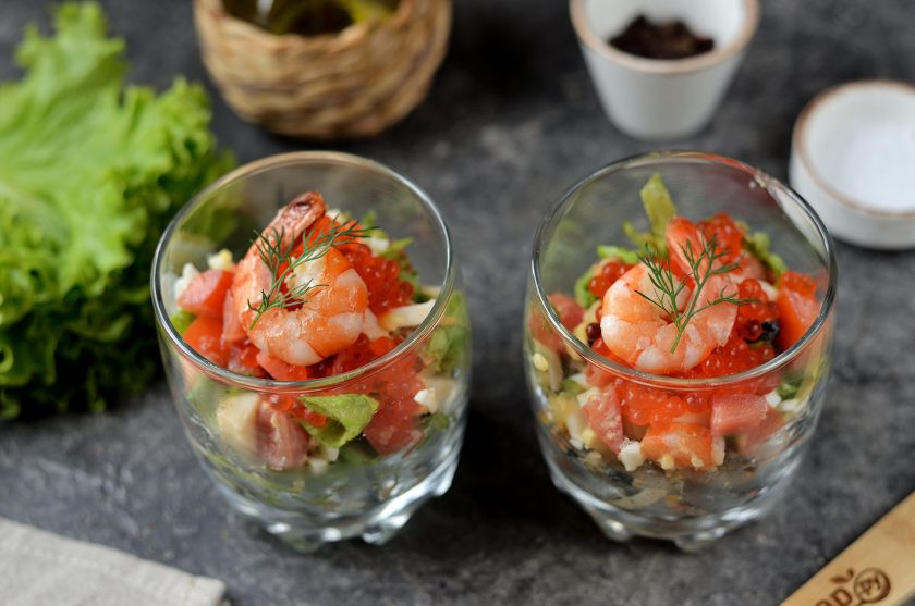 1. Этап. Салат с морепродуктами и красной икрой: Разложите салат в небольшие стаканы, сверху на салат выложите по полной чайной ложке красной икры с горкой, украсьте салат хвостиком крупной креветки и веточкой укропа.