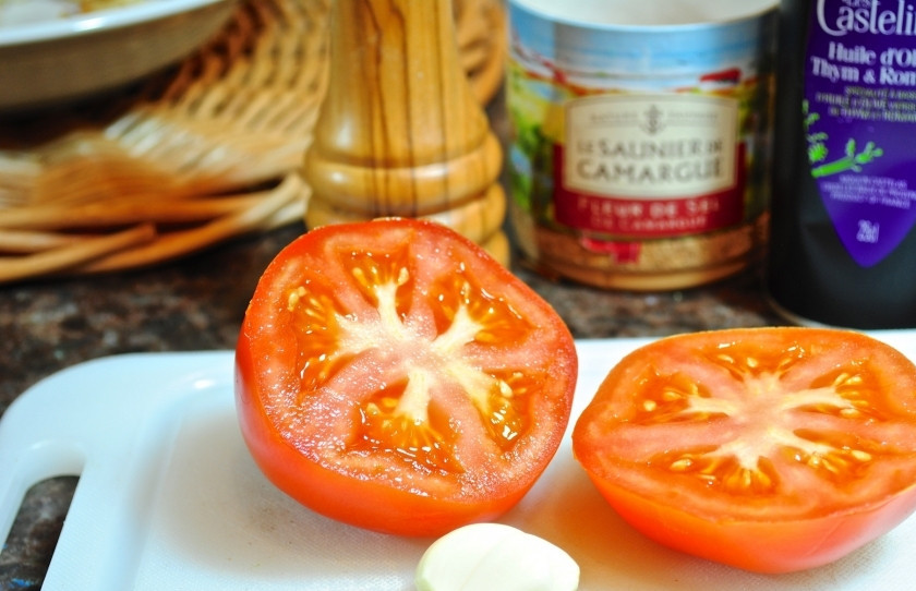 1. Этап. Тосты с помидорами: Разрежьте помидор на две половинки и почистите зубчик чеснока.