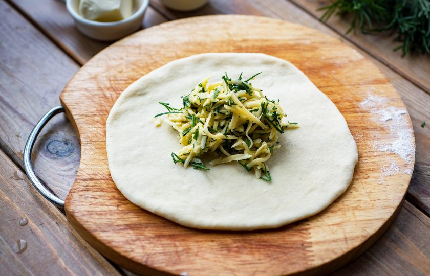 1. Этап. Хачапури на молоке с сыром: Одну часть теста раскатайте в лепешку и выложите в центр 1/6 часть от всей сырной начинки.