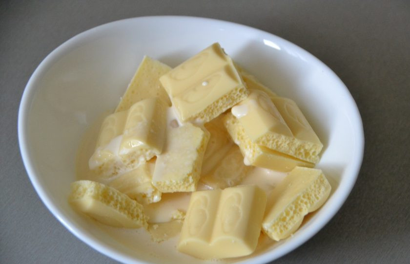 1. Этап. Мандариновый торт на Новый год: Разломите белый шоколад на дольки, добавьте 50 мл. сливок. Короткими импульсами по 10 секунд растопите в микроволновой печи, после каждого раза перемешивайте.