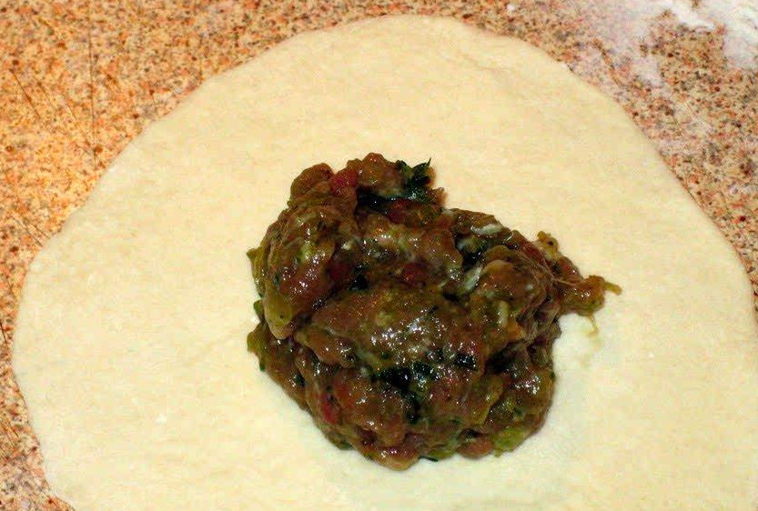 1. Этап. Хинкали со свининой: Каждую колбаску порежьте на кружочки. Раскатайте их, чтобы толщина слоя была около 3 мм. На каждый кружок выложите по столовой ложке начинки.