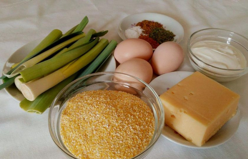 1. Этап. Кукурузно-сырная запеканка: Подготовьте все ингредиенты для приготовления кукурузно-сырной запеканки. При отсутствии лука-порея замените его другой зеленью или обычным репчатым луком.