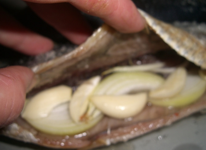 1. Этап. Копченая селедка: 2. Добавляем специи и укладываем внутрь нарезанный кольцами лук и мелко нарезанный чеснок. Оставляем минут на 20, как раз пока нагреется духовка.