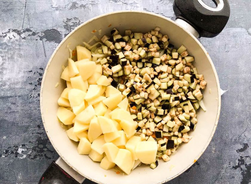 1. Этап. Овощное рагу с капустой и фасолью: Картофель хорошо помойте, почистите, нарежьте небольшими кусочками. Нарезанный картофель и баклажан высыпьте в сковороду.