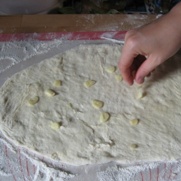 1. Этап. Пицца по-домашнему: Раскладываем на тесте дольки чеснока.