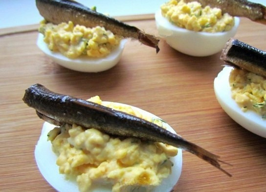 1. Этап. Фаршированные яйца со шпротами и красной икрой: 7. Кладу рыбку животиком вниз в начинку на яйце.