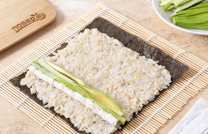 1. Этап. Роллы с бурым рисом: Добавьте сливочный сыр, нарезанный огурец и авокадо.