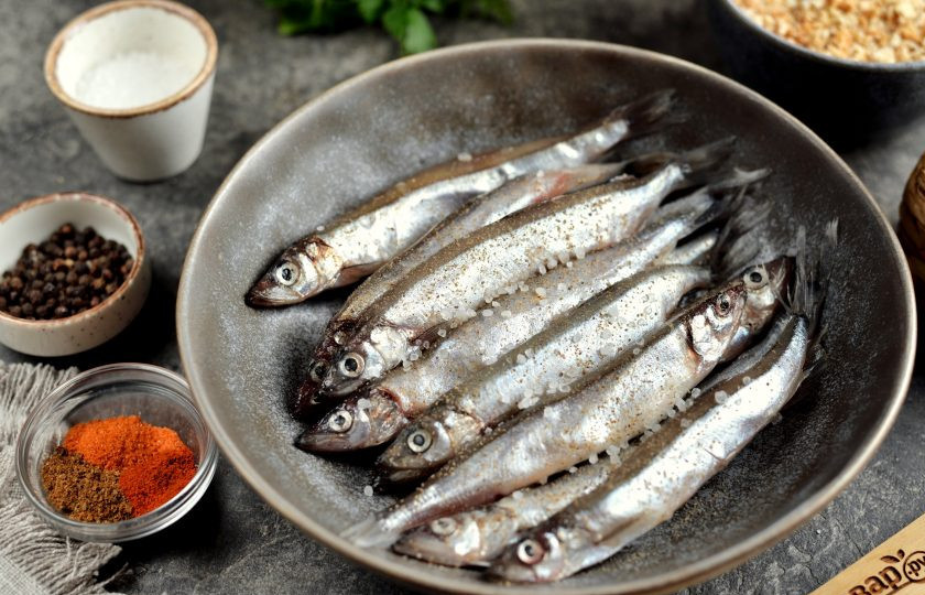 1. Этап. Мойва с корочкой в духовке: Чистить мойву не нужно, особенно, если большая ее часть с икрой. Переложите рыбку в глубокую миску, чуть посолите и поперчите.