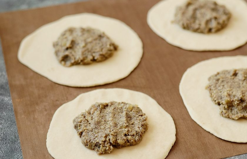 1. Этап. Беляши с грибами: Раскатайте каждый шарик, в центр выложите начинку из грибов.