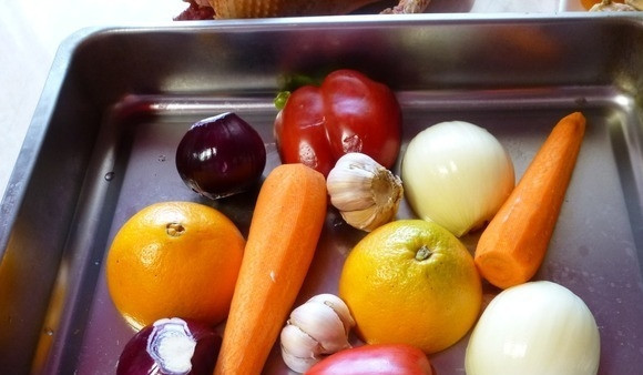 1. Этап. Гусь на луковой подушке: После этого все овощи и апельсин помойте. Всё, что необходимо, очистите от кожуры. Уложите продукты на противень.