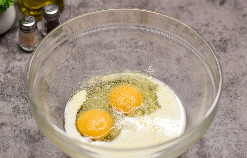 1. Этап. Быстрая пицца на сковороде из лаваша с яйцом: В миску вбейте несколько яиц, добавьте молоко, соль и перец по вкусу. По желанию добавьте немного сушеного чеснока.