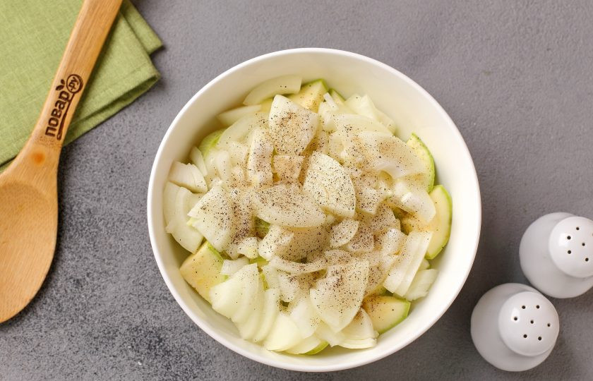 1. Этап. Цукини с курицей в духовке: Добавьте к кабачку нарезанный произвольно лук. Я нарезала четвертинками. Овощи посолите, поперчите и влейте масло.