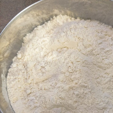 1. Этап. Дрожжевые оладьи на кукурузной муке: Отдельно просейте оба вида муки. Добавьте соль и дрожжи. Все тщательно перемешайте.