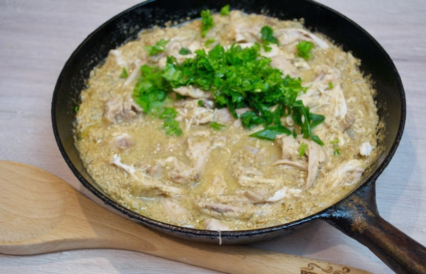 1. Этап. Классический сациви из курицы по-грузински: Зелень нарежьте и добавьте в соус. Выдавите чеснок, его тоже добавьте его в соус. Снова перемешайте.