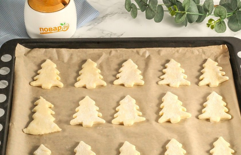 1. Этап. Творожное печенье «Елочки»: Разогрейте духовку до 160 градусов и выложите заготовки на пергаментную бумагу или противень.