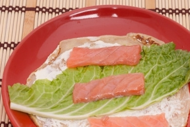 1. Этап. Рулетики из блинов с семгой: И теперь собираем наши рулетики. На блин намажем сливочный сыр. Сливочный сыр можно заменить плавленным и приготовить вот такую начинку - натереть плавленный сыр на мелкую терку и смешать с майонезом. Сверху на слой сыра кладем лист пекинской капусты и полоску семги.