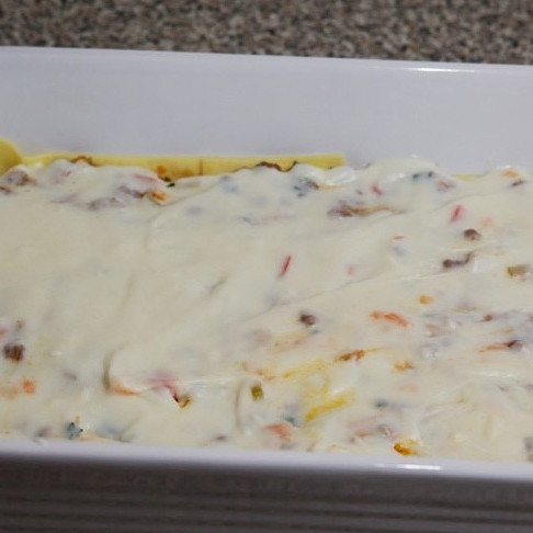 1. Этап. Лазанья с мясом: Разравниваем слой начинки, сверху заливаем небольшим количеством (примерно 1/4 часть) соуса бешамель.