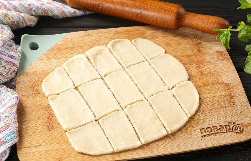 1. Этап. Вареницы с творогом в мультиварке: Разделите тесто для удобства на три части. Каждую часть раскатайте в пласт толщиной 3–4 мм. и нарежьте небольшими квадратиками.