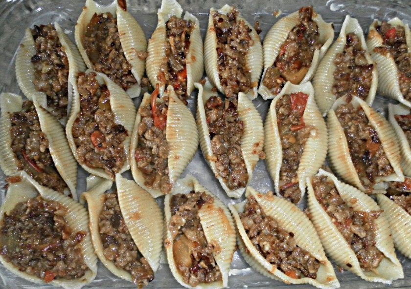 1. Этап. Ракушки под соусом Бешамель: 2. Баклажан мою, нарезаю мелко, солю и оставляю на 5-10 минут. Помидоры мою и нарезаю дольками, лук чищу и нарезаю мелко, одну часть обжариваю на сковороде, а вторую обжариваю на отдельной сковороде с баклажаном и томатами. Мясо мою и измельчаю через мясорубку с чесноком. Смешиваю все составляющие, вбиваю яйцо, солю по вкусу и добавляю специи, перемешиваю. Ракушки начиняю фаршем и складываю в форму для выпечки.