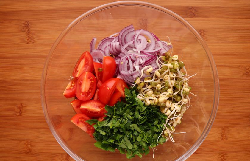 1. Этап. Салат с пророщенным машем: Нарежьте лук, помидоры и петрушку. Смешайте их в салатнике с пророщенным машем.