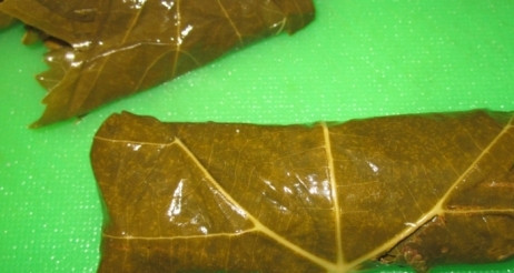 1. Этап. Цыплята в духовке: Маринованные листья винограда промываем водой и высушиваем. Затем выкладываем в них начинку и заворачиваем в рулетики.