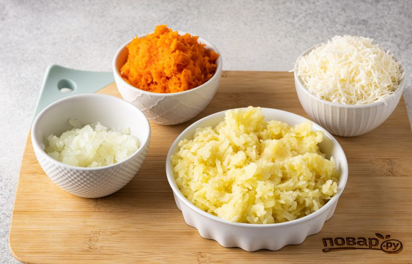 1. Этап. Вегетарианский салат в виде Кролика на Новый год 2023: Очистите и натрите на тёрке картофель и морковь. Лук нарежьте на мелкие кубики, ошпарьте кипятком и промойте в холодной воде, отожмите и откиньте на сито. Веганский сыр натрите на мелкой терке.