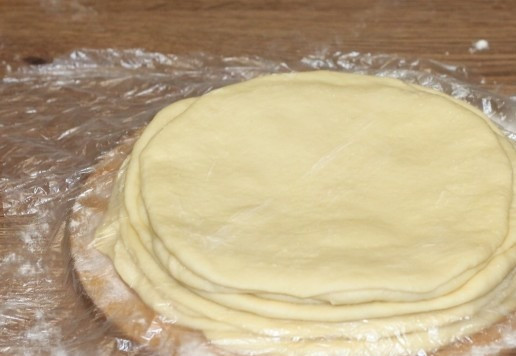 1. Этап. Пирожки из слоеного теста на кефире: 11. Подпыляем разделочную доску мукой, кладем стопки кружочков и закрываем каждую пленкой и прозрачным пакетом. Убираем кружочки в морозилку на 30 минут или в холодильник на всю ночь.