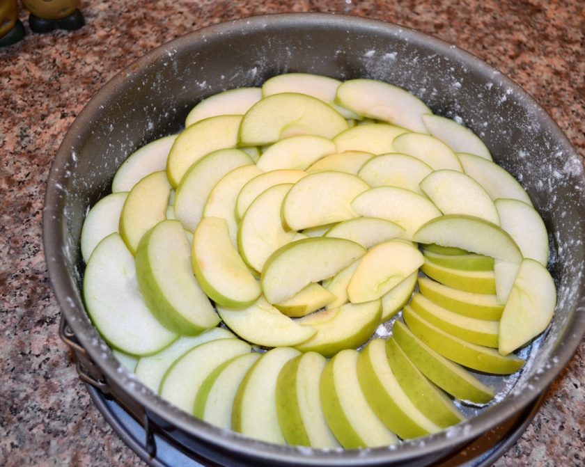 1. Этап. Яблочная шарлотка простая: 2. Нарежьте яблоки полукольцами. Форму для выпекания смажьте маслом и присыпьте немного мукой. Теперь нужно выложить яблоки так, чтобы не оставалось промежутков.