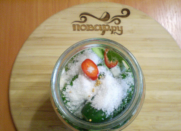 1. Этап. Острые маринованные огурчики на зиму: Утрамбуйте их в банки. Добавьте соль, сахар.