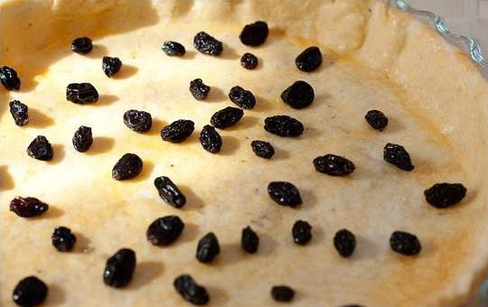 1. Этап. Печеночный пирог: 5. Соедините в маленьком сотейнике или кастрюле изюм, ром (можно заменить коньяком) и 1 ст. ложку воды. Доведите все это до кипения и остудите. Изюм равномерно выложите на испеченную основу для пирога (жидкость не выливайте).