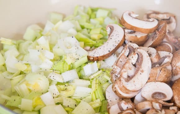 1. Этап. Куриные бёдра в сливочном соусе: 2. Нарежьте слайсами грибы, а лук - кубиками. Выложите ингредиенты в разогретое сливочное масло. Добавьте соль и перец. Жарьте 10 минут.