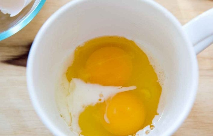 1. Этап. Омлет в микроволновке за 5 минут: 1. Смажьте чашку растительным маслом (любым по вкусу), чтобы омлет не приставал к ее бокам. Вбейте в чашку 2 яйца, влейте столовую ложку молока.