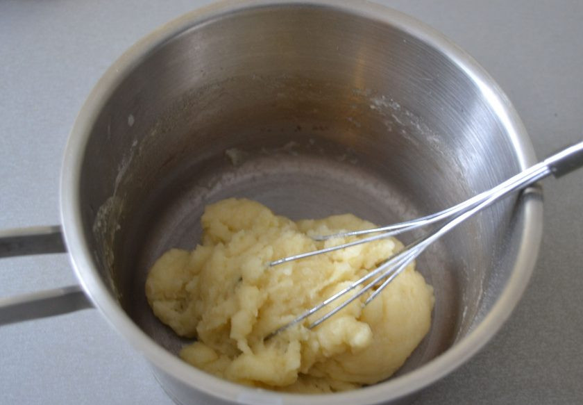 1. Этап. Лимонные эклеры: Всыпьте разом всю муку и интенсивно мешайте, пока тесто не соберется в комок и не отстанет от стенок сотейника, слегка подсушите его. Снимите тесто с огня, охладите.