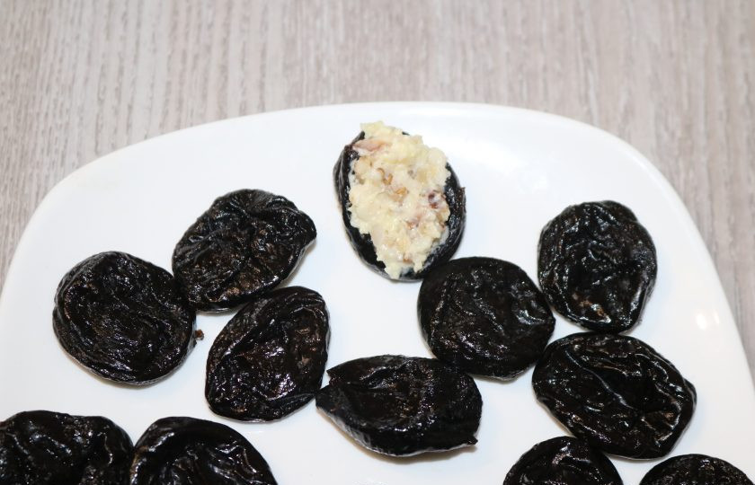 1. Этап. Чернослив фаршированный грецкими орехами: Чернослив должен быть мягким. Если у вас твёрдый, залейте его на 1-2 минуты кипятком. Чернослив немного надрежьте маленьким ножом. Нафаршируйте начинкой.