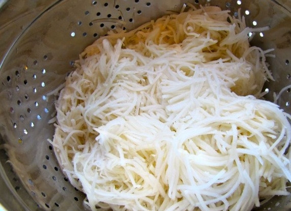 1. Этап. Латкес: Откиньте тертый картофель на дуршлаг, выжмите как можно больше жидкости.