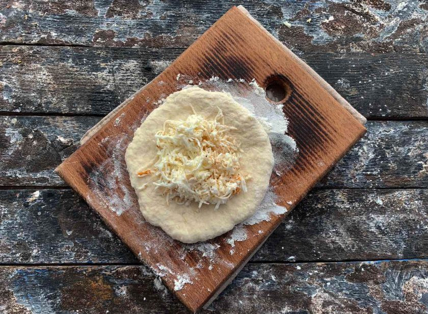 1. Этап. Адыгейские лепешки на кефире: Тесто разделите на несколько частей. Каждую часть раскатайте в небольшую лепешку, в центр выложите начинку из сыра.