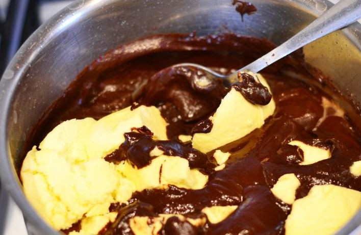 1. Этап. Шоколадный пирог (простой рецепт): Сливочное масло порежьте кубиками. Добавьте его в сотейник к остальным ингредиентам. Тщательно все перемешайте, чтобы масло распалилось в горячей массе.