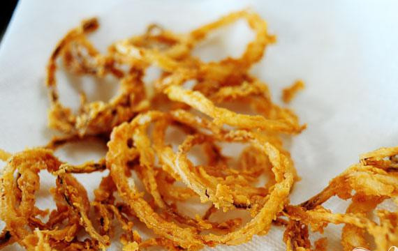 1. Этап. Салат со стейком: 4. Сделать луковые колечки. Смешать сухие ингредиенты и отложить в сторону. Нагреть масло в сковороде. Взять некоторую часть лука, добавить в мучную смесь, стряхнуть избытки и окунуть в горячее масло. Обжарить в течение нескольких минут до золотисто-коричневого цвета и выложить на бумажное полотенце.