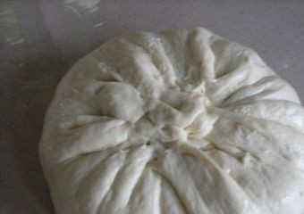 1. Этап. Осетинский пирог с картошкой: Возьмите блин из теста за края и соберите их в мешочек. Хорошо залепите края и снова придайте тесту форму блина.