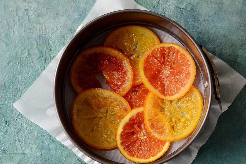 1. Этап. Постный пирог с маком и апельсином: Выложите карамелизированные апельсины в застеленную форму для выпечки.