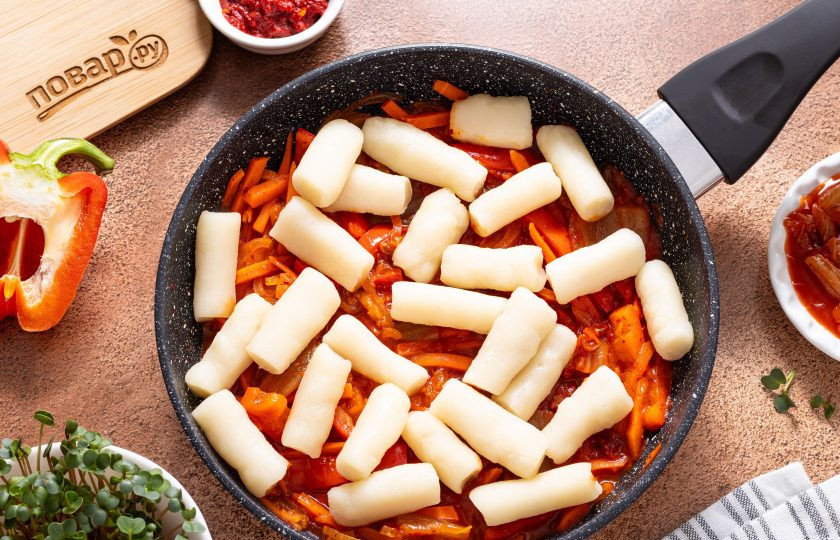 1. Этап. Токпокки с кимчи: Выложите токпокки в сковороду. Если используете замороженный полуфабрикат, то предварительно подготовьте его по инструкции.