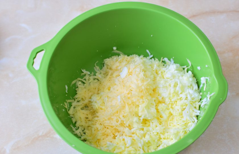 1. Этап. Тарталетки с сыром и огурцом: Очистите яйца и потрите их на терке. Добавьте к яйцам тертый сыр.