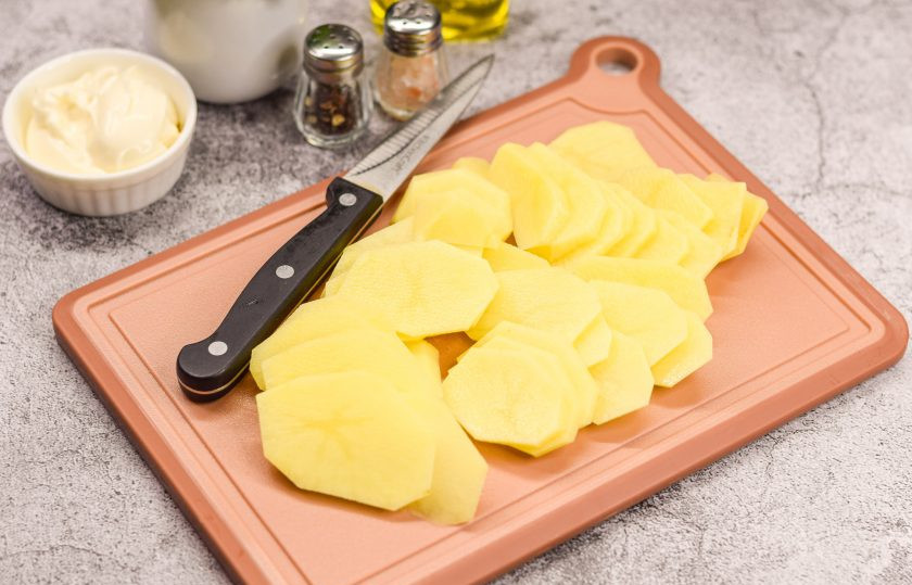 1. Этап. Классический рецепт мяса по-французски: Очистите картофель и вымойте, просушите. Нарежьте картофель тонкими пластинами.