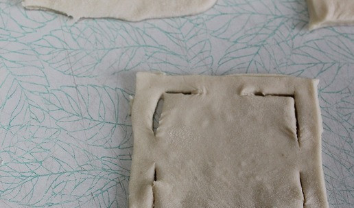 1. Этап. Пирожки закусочные с курицей: Слоеное тесто раскатать и разрезать на квадраты. Надрезать уголки