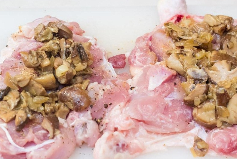 1. Этап. Фаршированные куриные окорочка в духовке: 3. Займёмся теперь начинкой. Грибы промываем, очищаем и нарезаем маленькими кусочками. Обжариваем грибы на сковороде с добавлением растительного или оливкового масла. Очищаем лук, нарезаем его мелко и обжариваем на отдельной сковороде, после чего соединяем грибы и лук. На кусочки мяса выкладываем получившуюся начинкую