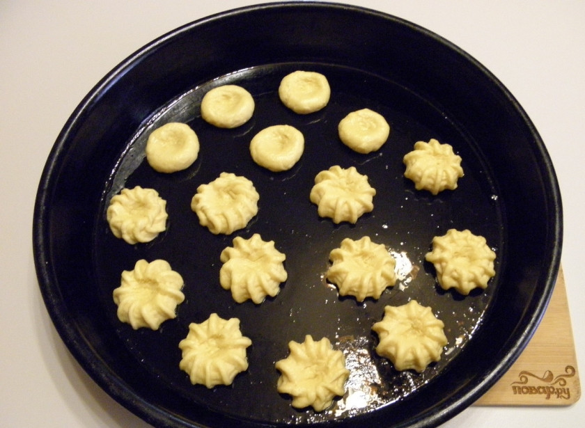 1. Этап. Песочное печенье с вареньем: С помощью насадки и кондитерского мешка отсадите печенье на противень смазанный жиром. Сделайте пальцами углубление по серединке. Если у вас нет мешка, не беда, скатайте тесто шариками и сделайте углубление.