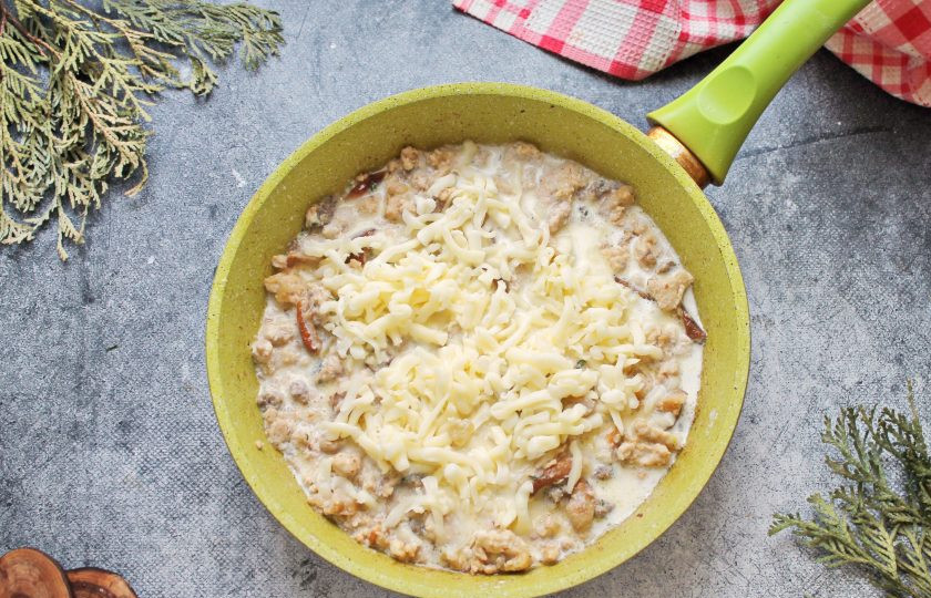 1. Этап. Паста с фаршем и белыми грибами: Влейте в сковороду сливки, добавьте сыр и перемешайте. Доведите все по вкусу на соль, поперчите и доведите до кипения.