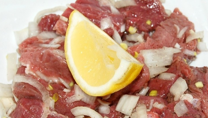 1. Этап. Шашлык на сковороде из говядины: Поливаем мясо с луком соком половинки лимона. Если косточки упадут в тарелку к мясу, то их нужно достать, иначе говядина будет горчить. Еще раз все перемешиваем, накрываем тарелку крышкой и ставим на 1-2 часа холодильник, можно мариновать и дольше.